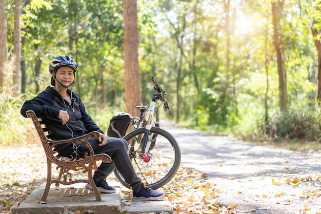 Hogere Aziatische vrouwenfiets met het zitten in het park