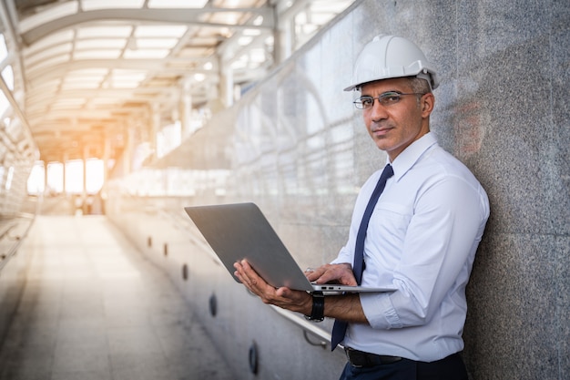 Hogere ingenieur die een tabletcomputer in een openluchtfabriek van het het werkterrein met behulp van.