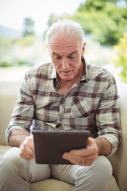 Hogere mens die digitale tablet in woonkamer gebruiken