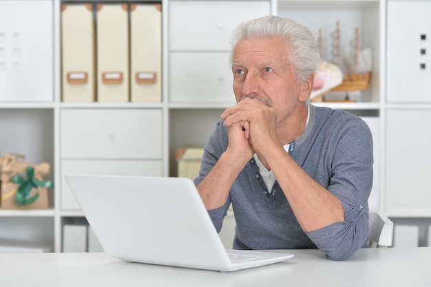 Hogere mens die laptop thuis met behulp van