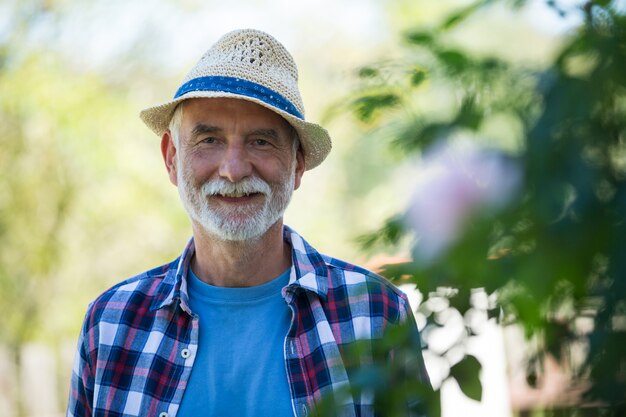 Hogere mens in hoed die zich in tuin bevindt