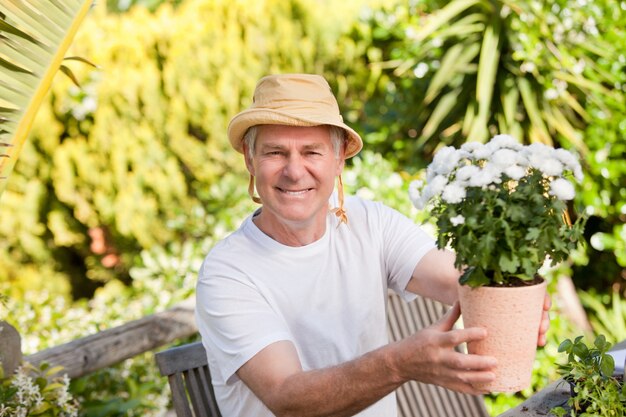 Hogere mens met bloemen in zijn tuin