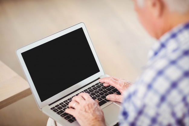 Hogere mensenzitting op bank en het gebruiken van laptop in woonkamer