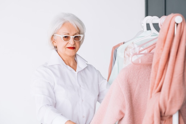 Hogere mode-stijl. Winkel ervaring. Oudere dame die naar de camera kijkt terwijl ze een outfit kiest.