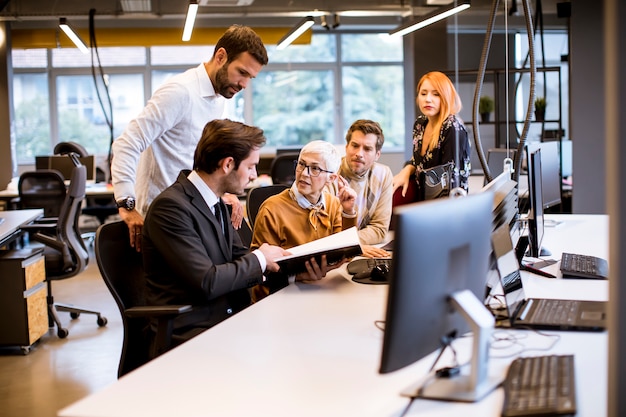 Hogere onderneemster die samen met jonge bedrijfsmensen in modern bureau werkt