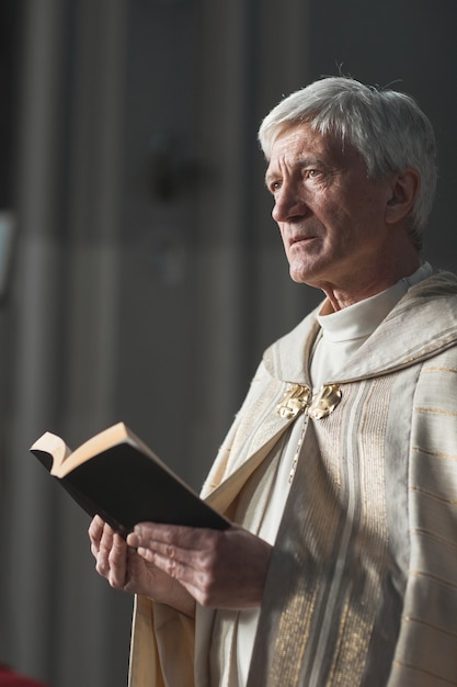 Hogere priester die met Bijbel staat en gebeden leest tijdens het huwelijk in de kerk