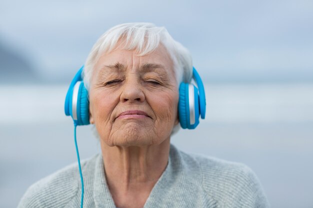 Hogere vrouw die aan muziek op hoofdtelefoons luistert