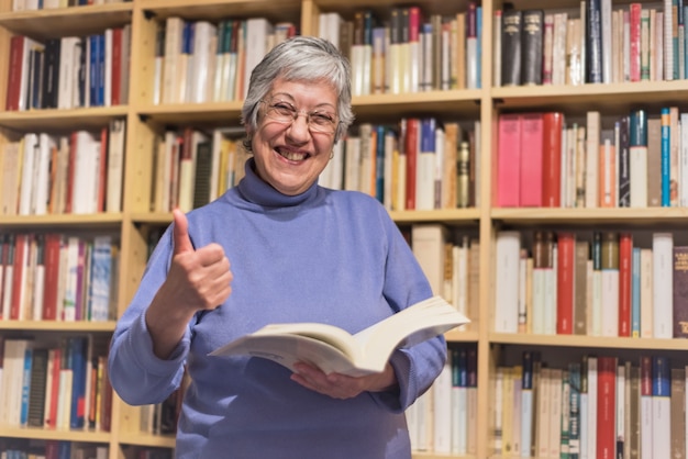 Hogere vrouw die een boek thuis leest