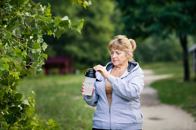 Hogere vrouw die een fles water houdt