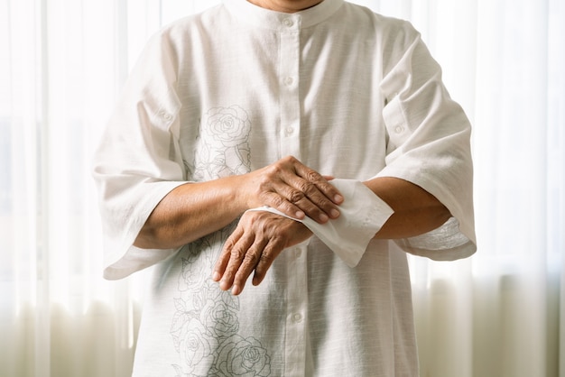 Hogere vrouw die haar handen met wit zacht papieren zakdoekje schoonmaakt. geïsoleerd op een witte achtergrond