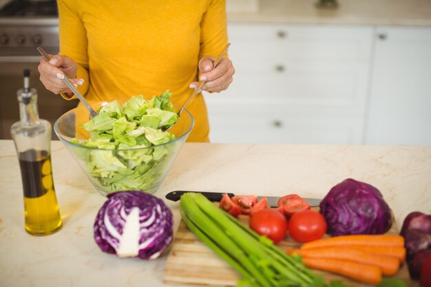 Hogere vrouw die plantaardige salade voorbereidt