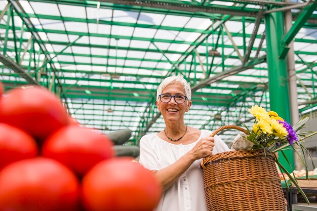 Foto hogere vrouw die verse organische groente op markt koopt