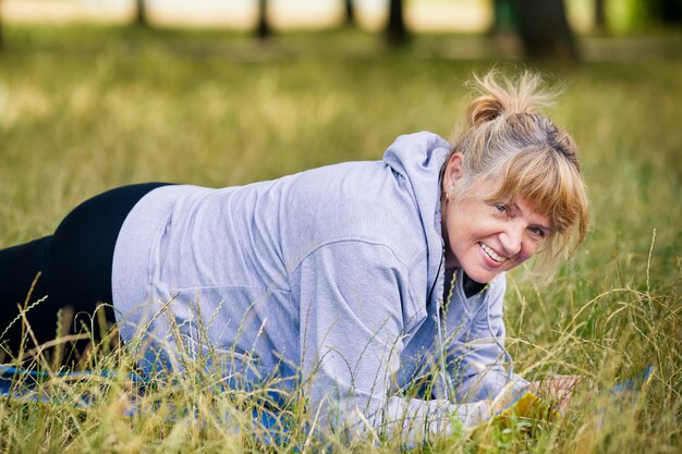 Hogere vrouw die yoga in het park doet