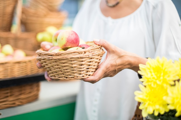 Hogere vrouw het kopen appelen in bakje op markt