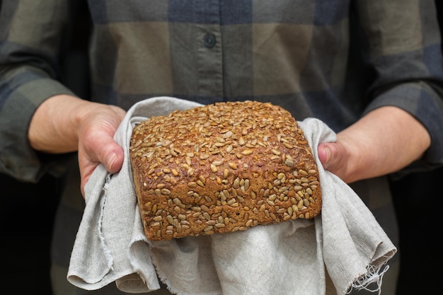 Hogere vrouwenhanden die vers gebakken brood van roggebrood houden