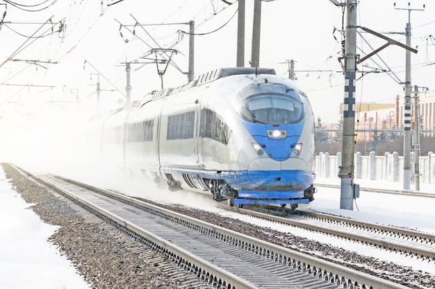 Hogesnelheidstrein rijdt in de winter met hoge snelheid door het besneeuwde landschap.