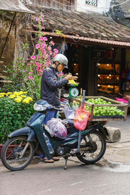 Hoi An, Vietnam - 17 februari 2016: Aziatische handelaar met een motorfiets die verse chayote verkoopt op de straatmarkt in Hoi An, Vietnam.