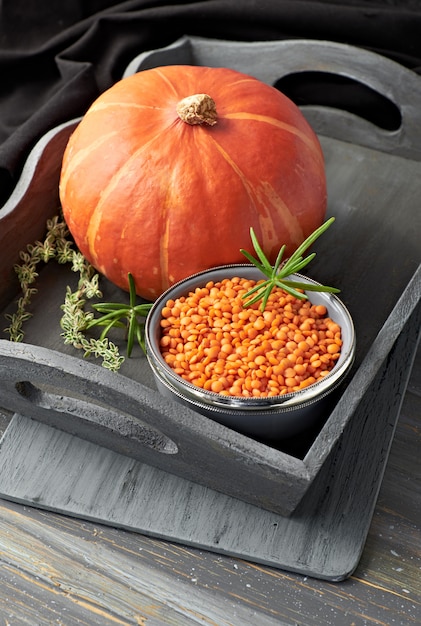 Hokkaido pumpkin and bowl of red lentils on gray rustic tray