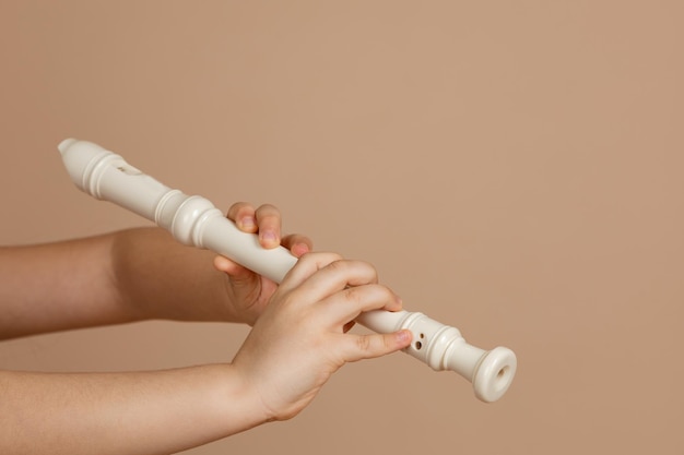 Hold fipple flute with both hands and pinch holes closeup beige background Woodwind musical instrument Aerophone or reedless wind instrument that produce sound from flow of air across opening