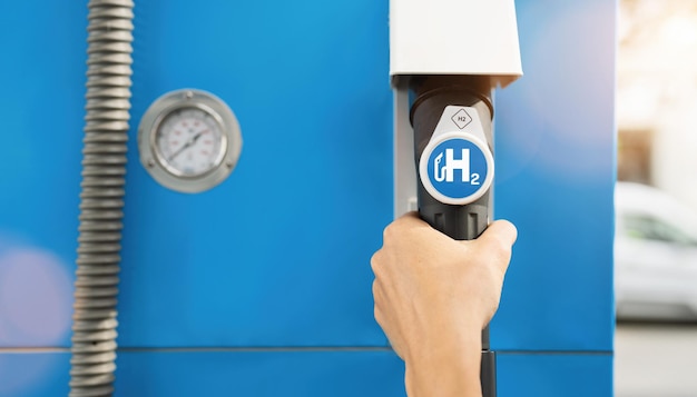 Hold a fuel dispenser with hydrogen logo on gas station h2 combustion engine for emission free eco friendly transport concept image