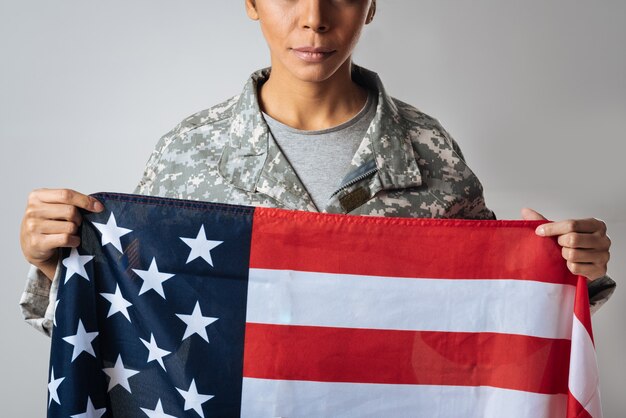 Hold on to my beliefs. Stunning resolute confident lady wearing her army uniform and holding up Stars and Stripes