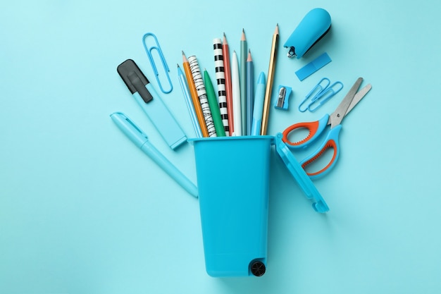 Holder in the form of trash can with stationery on blue background