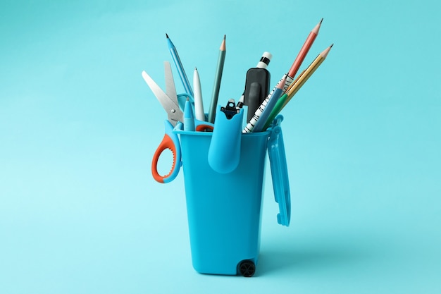 Holder in the form of trash can with stationery on blue background