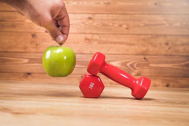 Holding an apple by a dumbbell on the table