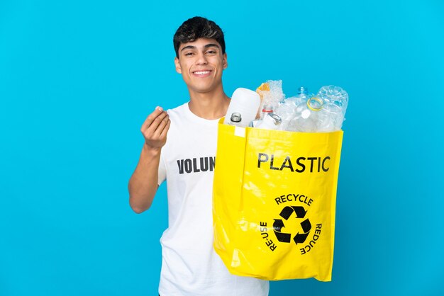 In possesso di un sacchetto pieno di bottiglie di plastica da riciclare su sfondo blu che fa gesto di denaro