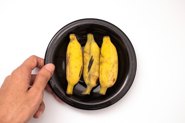 holding banana on a plate isolated on a white background