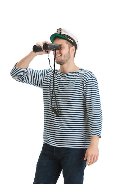 Holding binocular. caucasian male sailor in uniform on white studio wall.