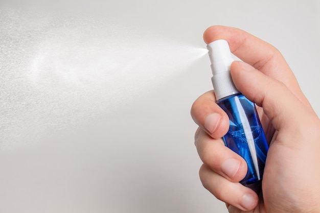 holding a blue spray bottle on white background.