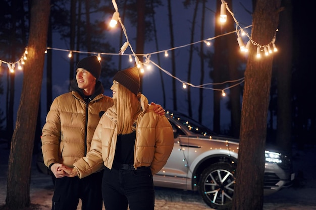 Holding by the hands Couple standing in the forest and celebrating New year