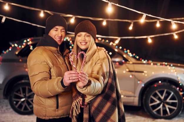 Holding candies Couple standing in the forest and celebrating New year