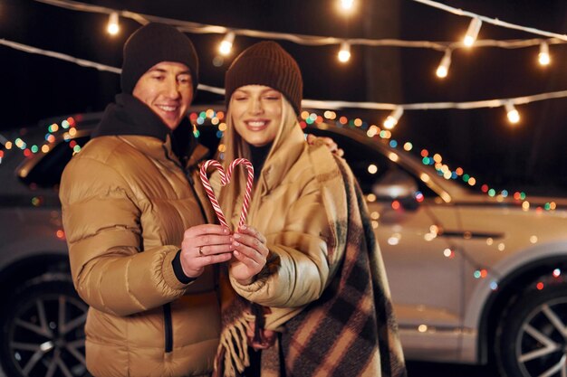 Holding candies Couple standing in the forest and celebrating New year