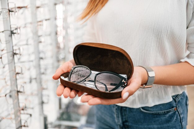 Holding case with glasses Woman is in the store Close up view