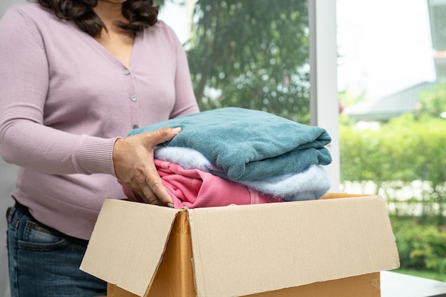 Holding clothing donation box with used clothes at home to\
support help for poor people in the world