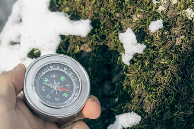 雪に覆われた苔の背景にコンパスを持って