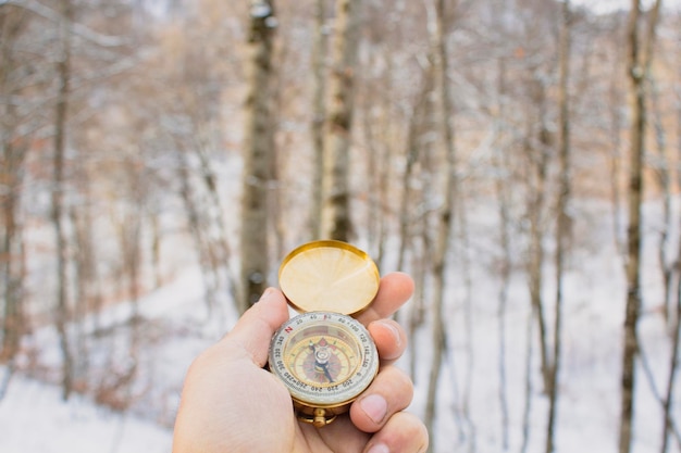 Holding a compass on the background of winter forest