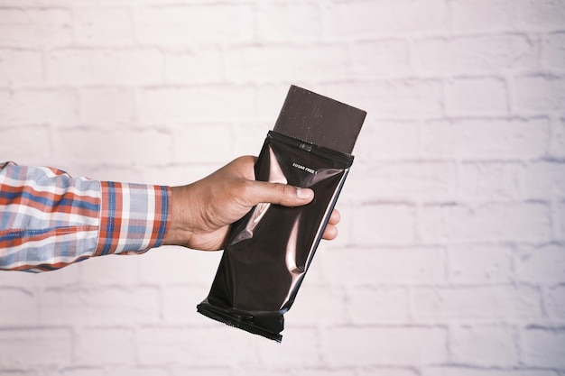 Holding dark chocolate against a white wall