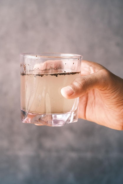 Holding dirty glass of water against black background