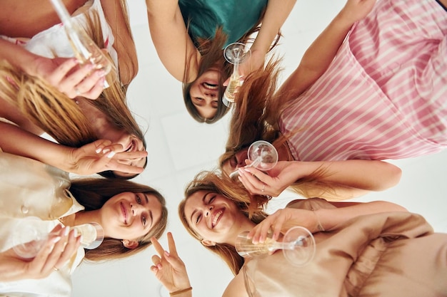 Holding drinks and looking down Group of happy women that is at a bachelorette party