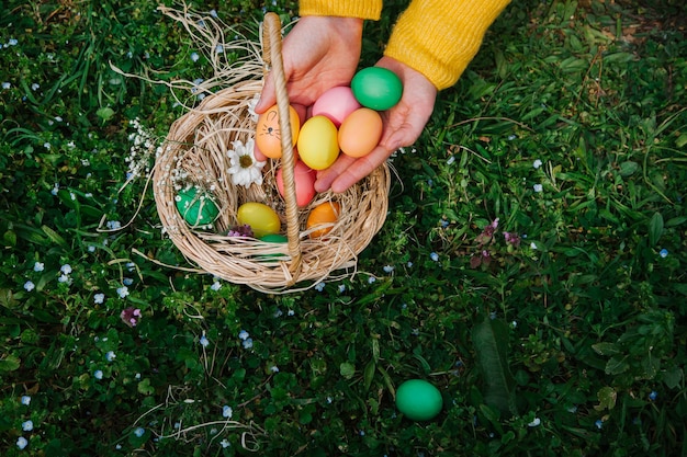 Фото Держа пасхальные яйца в корзине с цветами и конфетами