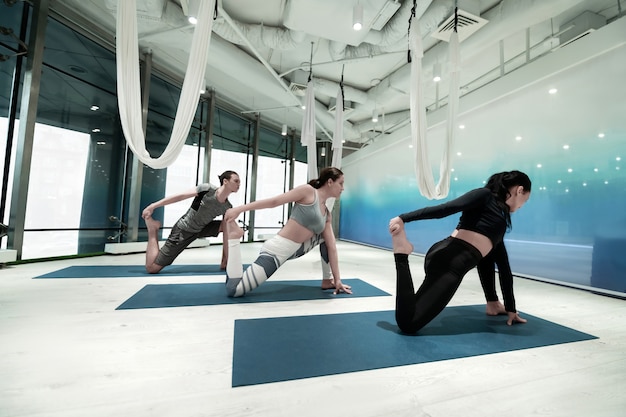 Holding foot. Two fit and slim women and man holding their foot while stretching doing yoga