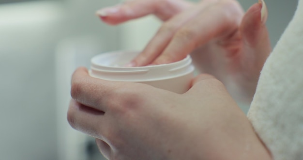 Photo holding a glass jar of skin cream the concept of beauty and health and skin care for the body closeup shot of hands applying moisturizer