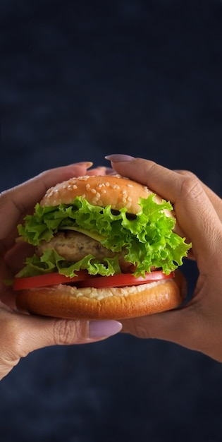 Держа гамбургер двумя руками