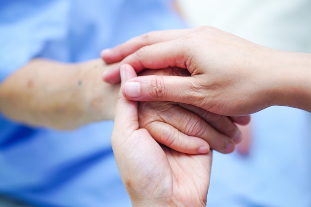Держа руку азиатских старшего или пожилой пожилой леди пациента с любовью, заботой, поощрять.