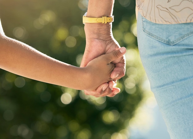 Holding hands mother and daughter in closeup outdoor and walking together with care love or bonding Mom young kid and summer sunshine in garden backyard or park for family vacation and freedom