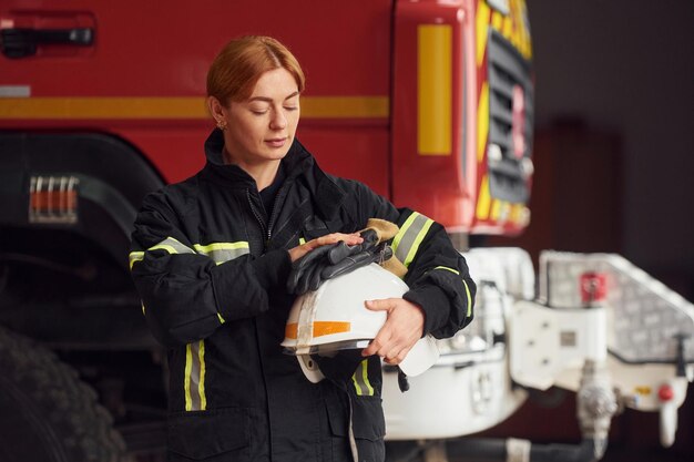 Photo holding helmet woman firefighter in uniform is at work in department