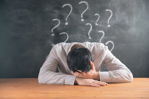 holding his head in his hands and behind a question mark .